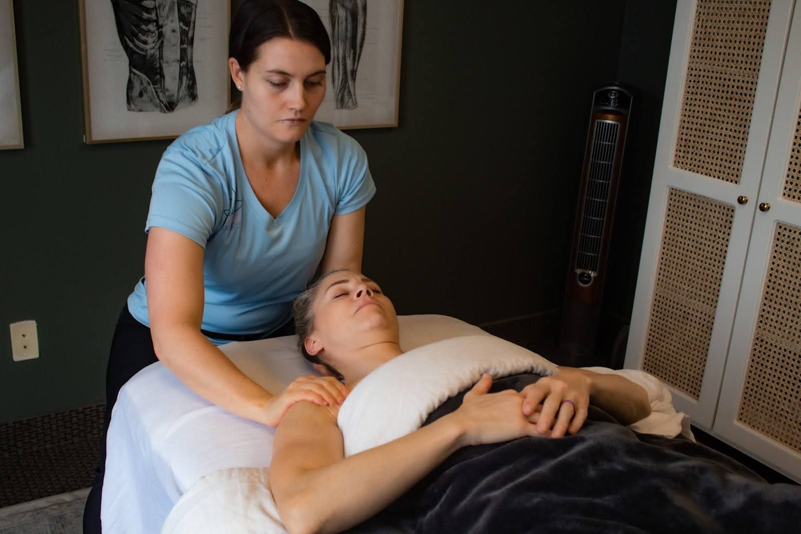 Therapist in a light blue Revive shirt working on a client's shoulders